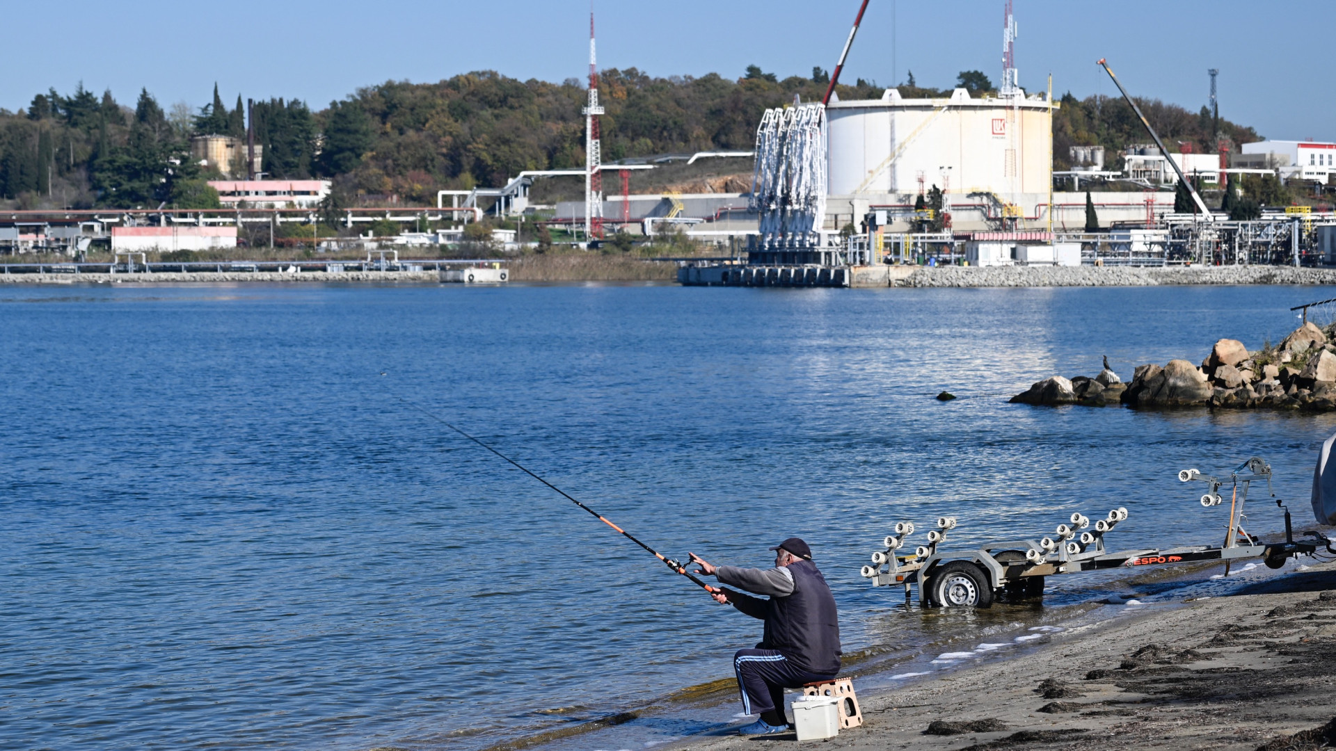 Рыбак на побережье Черного моря перед входом в терминал Лукойл в порту Розанец вблизи Бургаса, Болгария, 14 ноября 2025 года