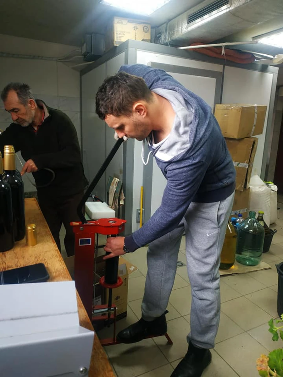 Микола Хижко та Богдан Павлій закупорюють пляшки з вином